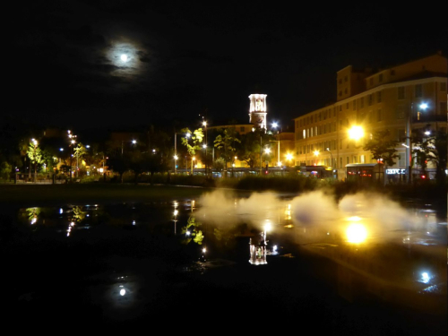 Nachthimmel mit Mond in Nizza, Spiegelung Kirche, Häuser, Park am Brunnen und künstlichem Nebel