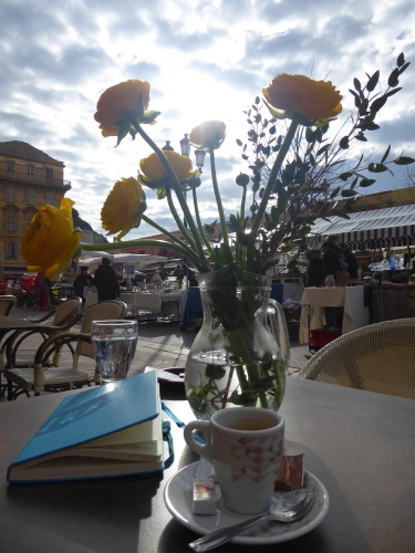 Tischdeko, Espresso und Buch im Cafe am Marktplatz in Nizza (hochkant)