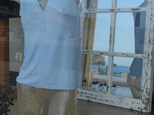 Durchs Fenster in die Spiegelung nach draußen an den Strand (Geschäft in Nazare) 