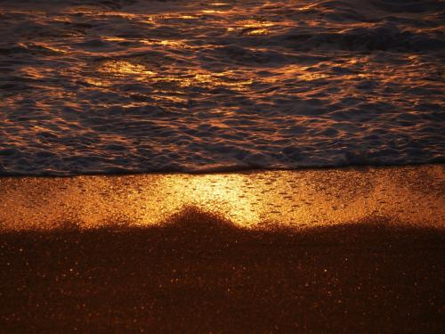 Goldene Spiegelung im Meer und Strand