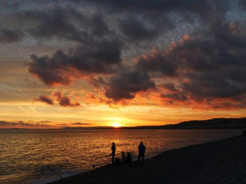 Fischer vor abendlichem wolkenverhangenem Himmel bei Sonnenuntergang in Nizza